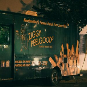 A vibrant food truck parked on the street at night, offering famous french fries.