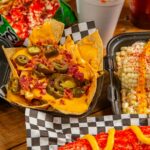 Close-up of Mexican street food with nachos, corn, and elote, showcasing bold flavors and colors.