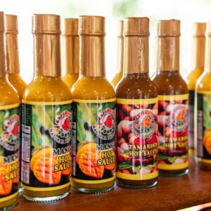 Colorful assortment of Trinidadian mango and tamarind hot sauces in bottles.